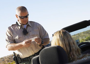 Florida Highway Patrol officer writing speeding ticket to driver on side of the road